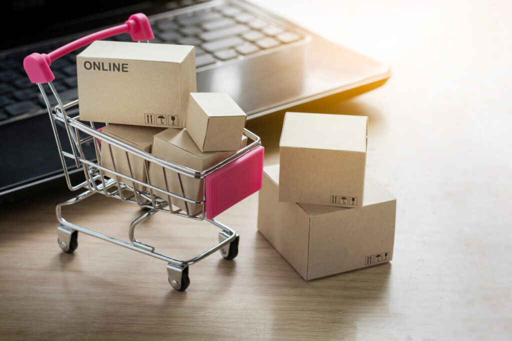 un caddie et des cartons de produits au format miniature sur un bureau devant un pc